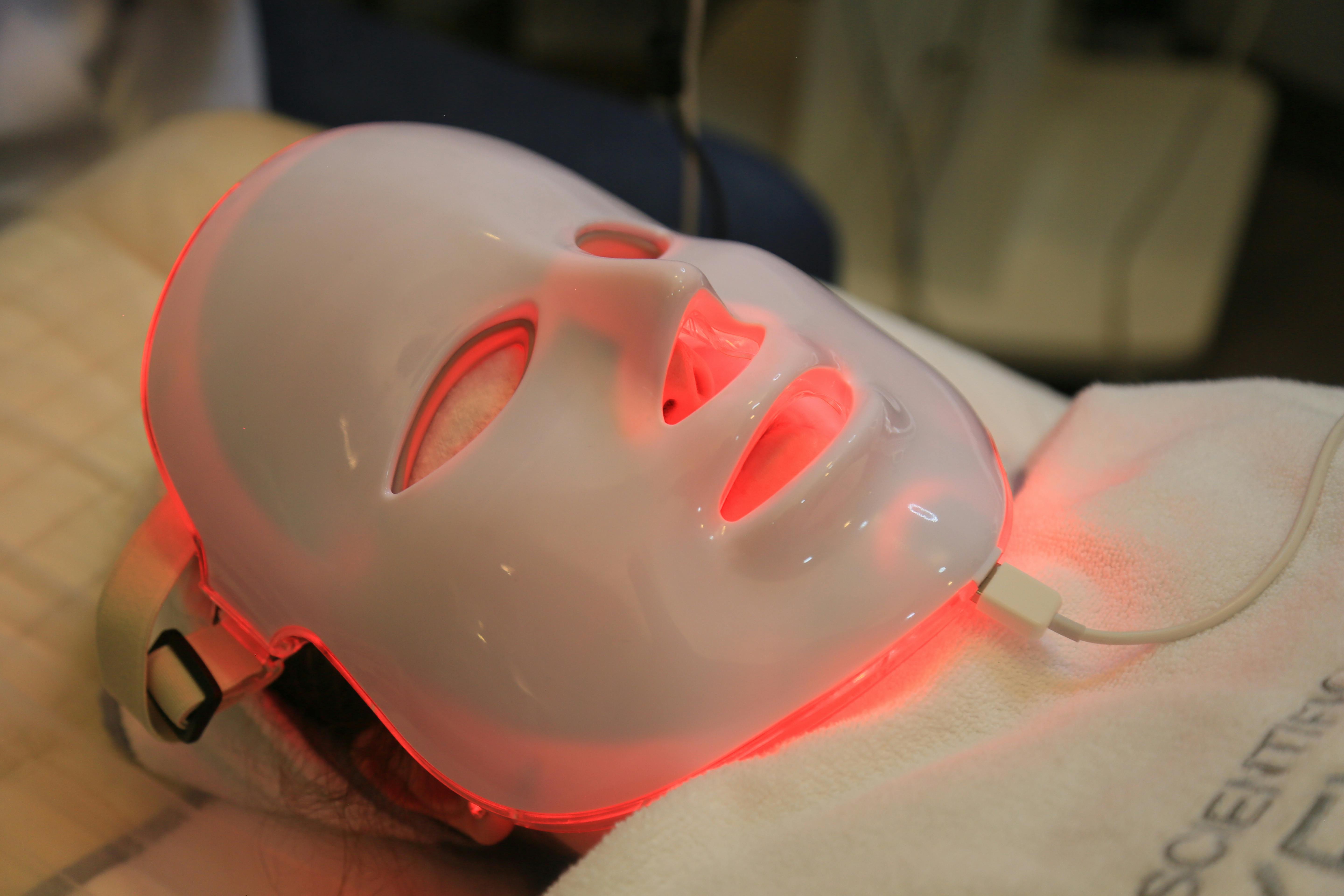 Close-up of an LED light therapy face mask with red light illumination on a person