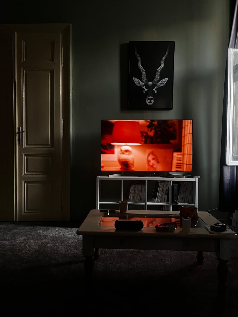 A dimly lit lounge with a television glowing across an empty couch, late evening