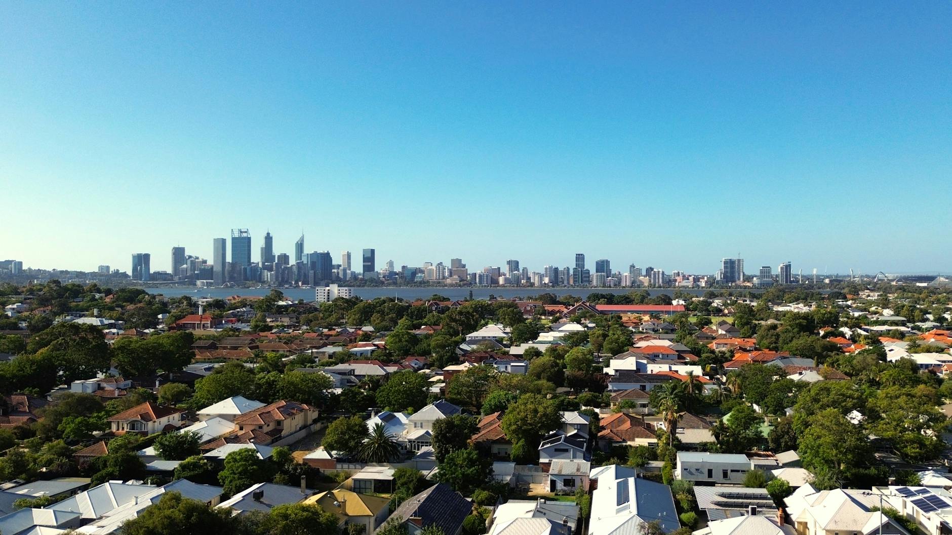 Aerial view of Perth's CBD towers and surrounding suburban rooflines under clear sky