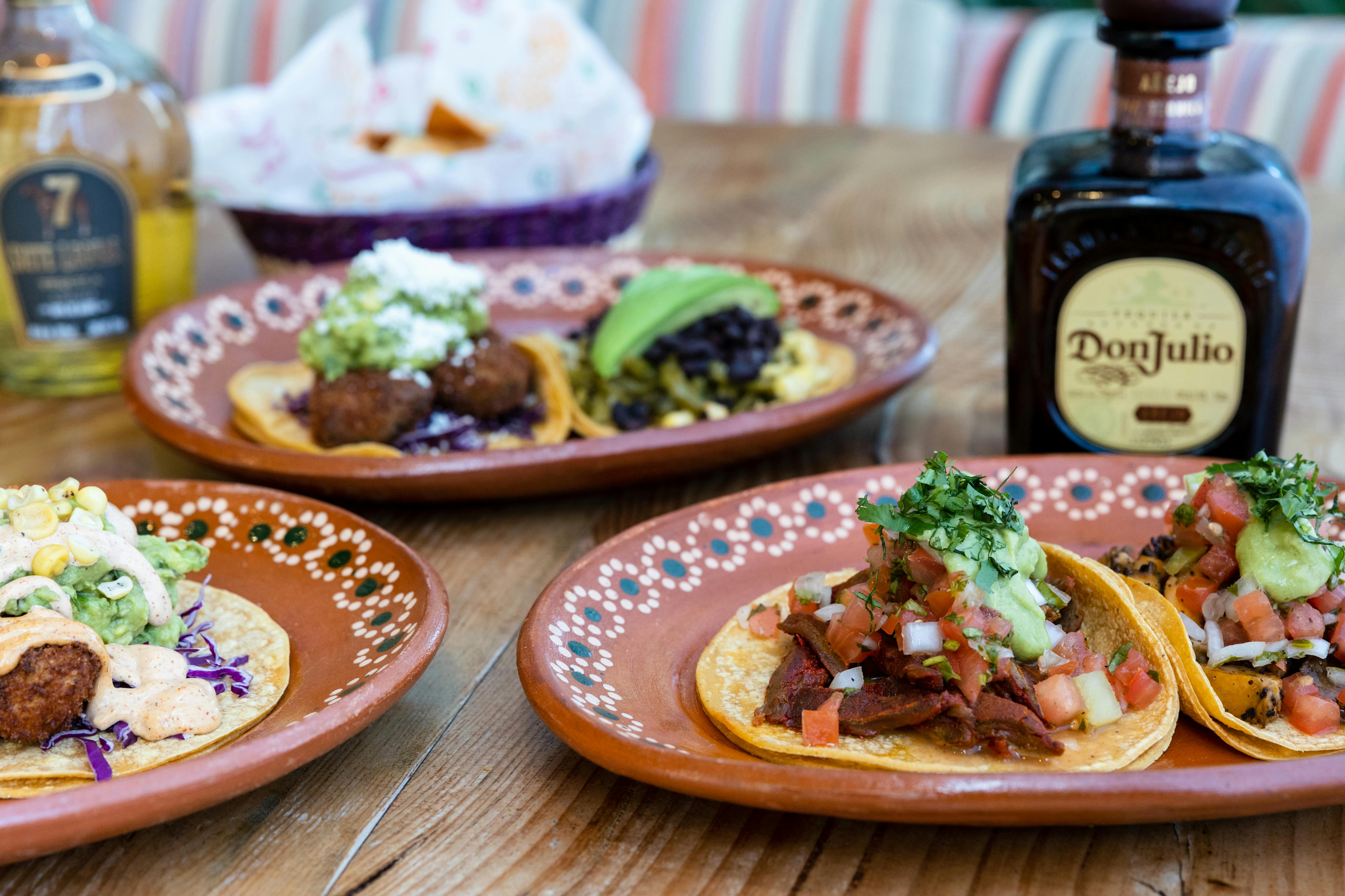 Authentic Mexican tacos served with tequila on a rustic table, lime and salsa on the side