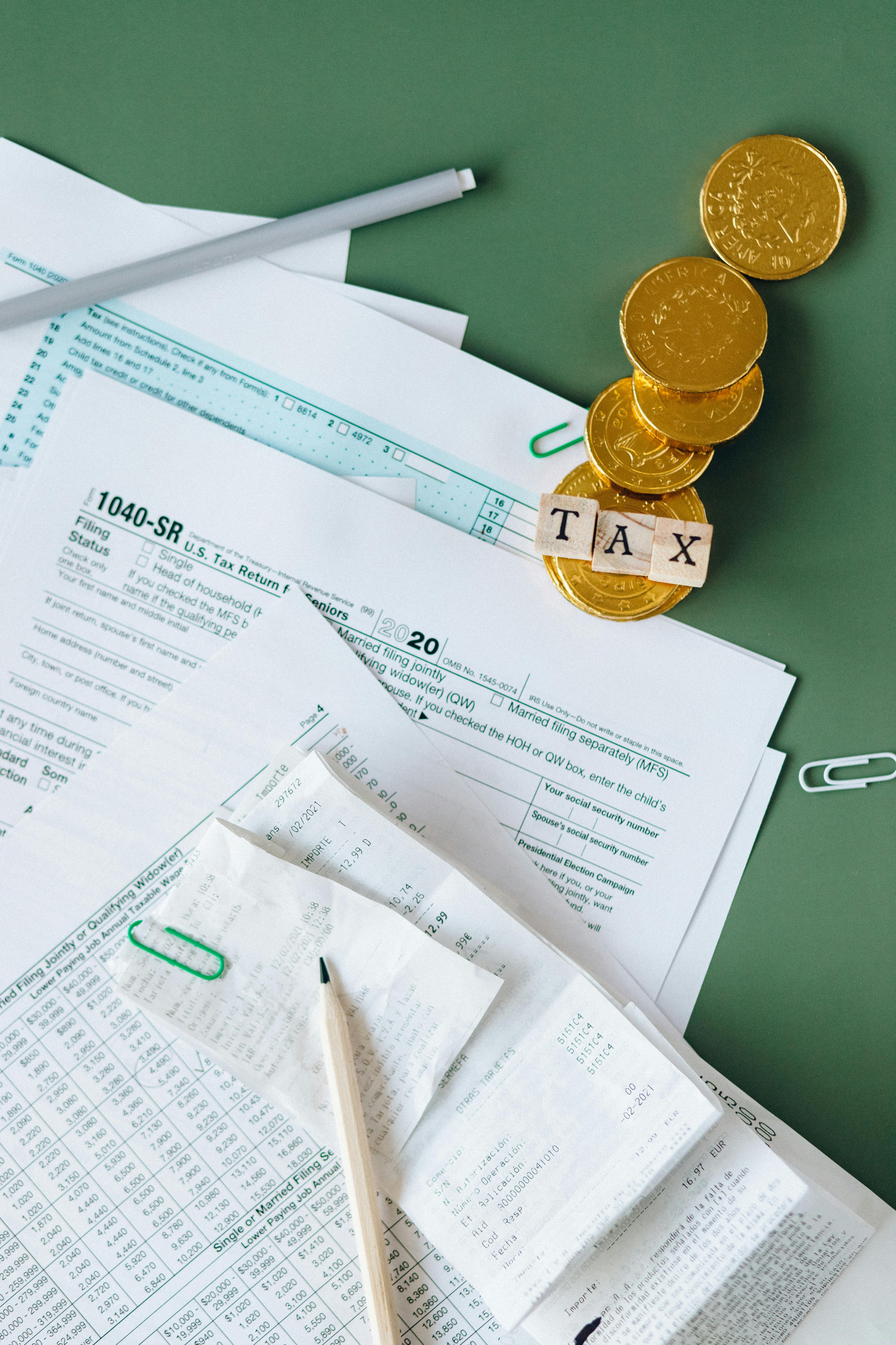 Tax documents and coins on a green desk symbolizing financial planning and savings