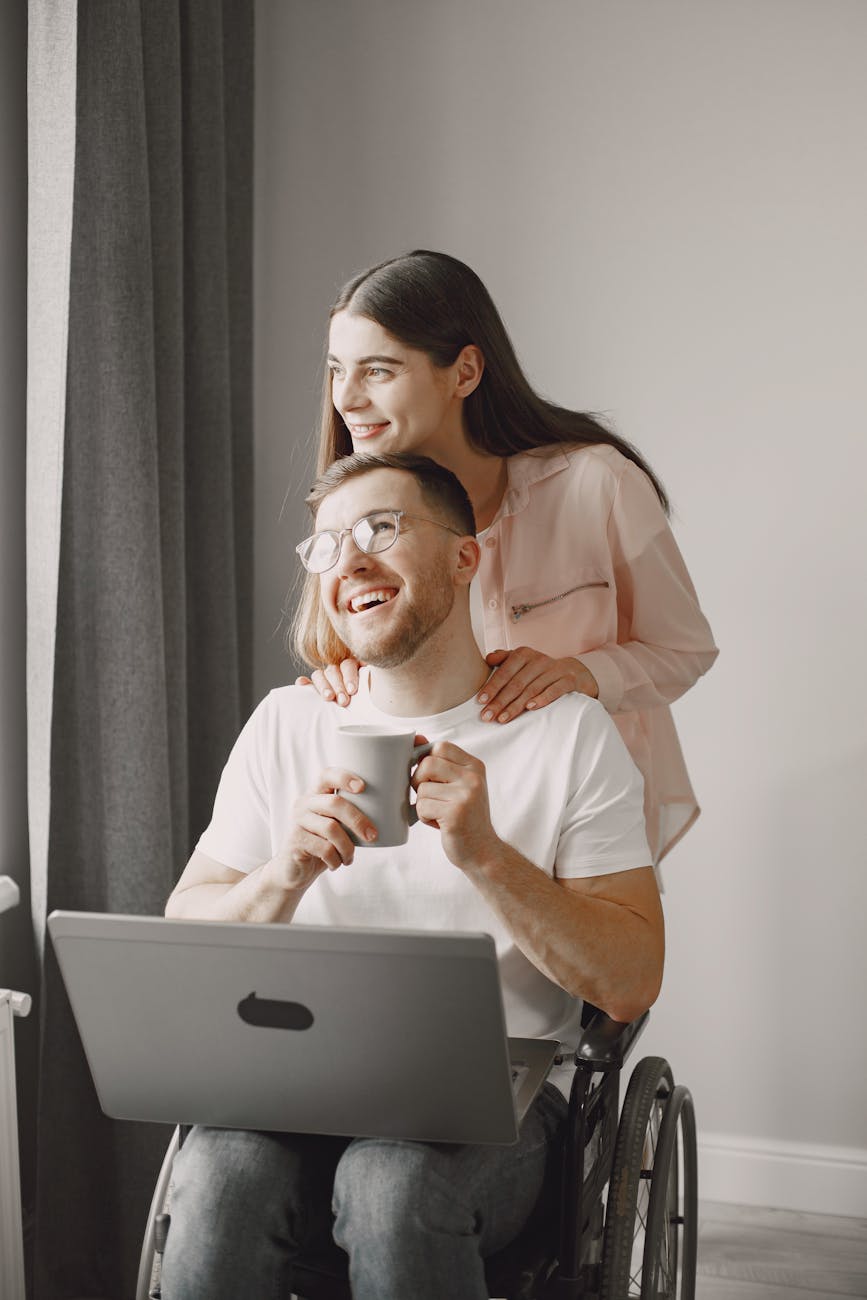 A happy couple in love, with a man in a wheelchair, enjoying a moment indoors.