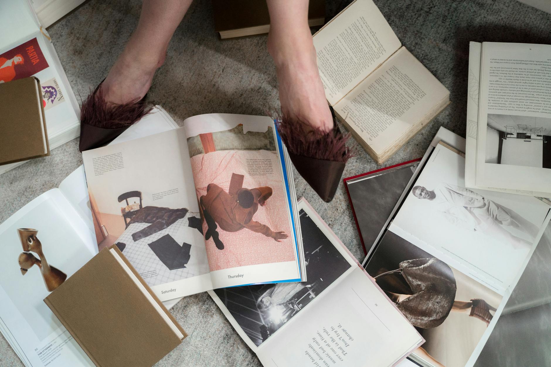Open fashion books on a carpet beside polished shoes