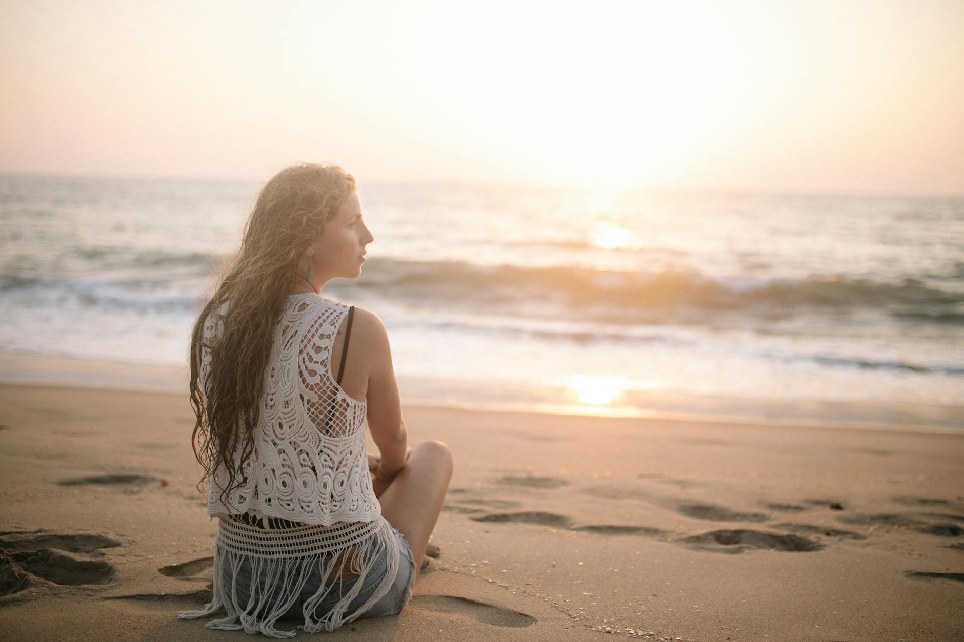 Woman meditating alone on a beach at sunrise