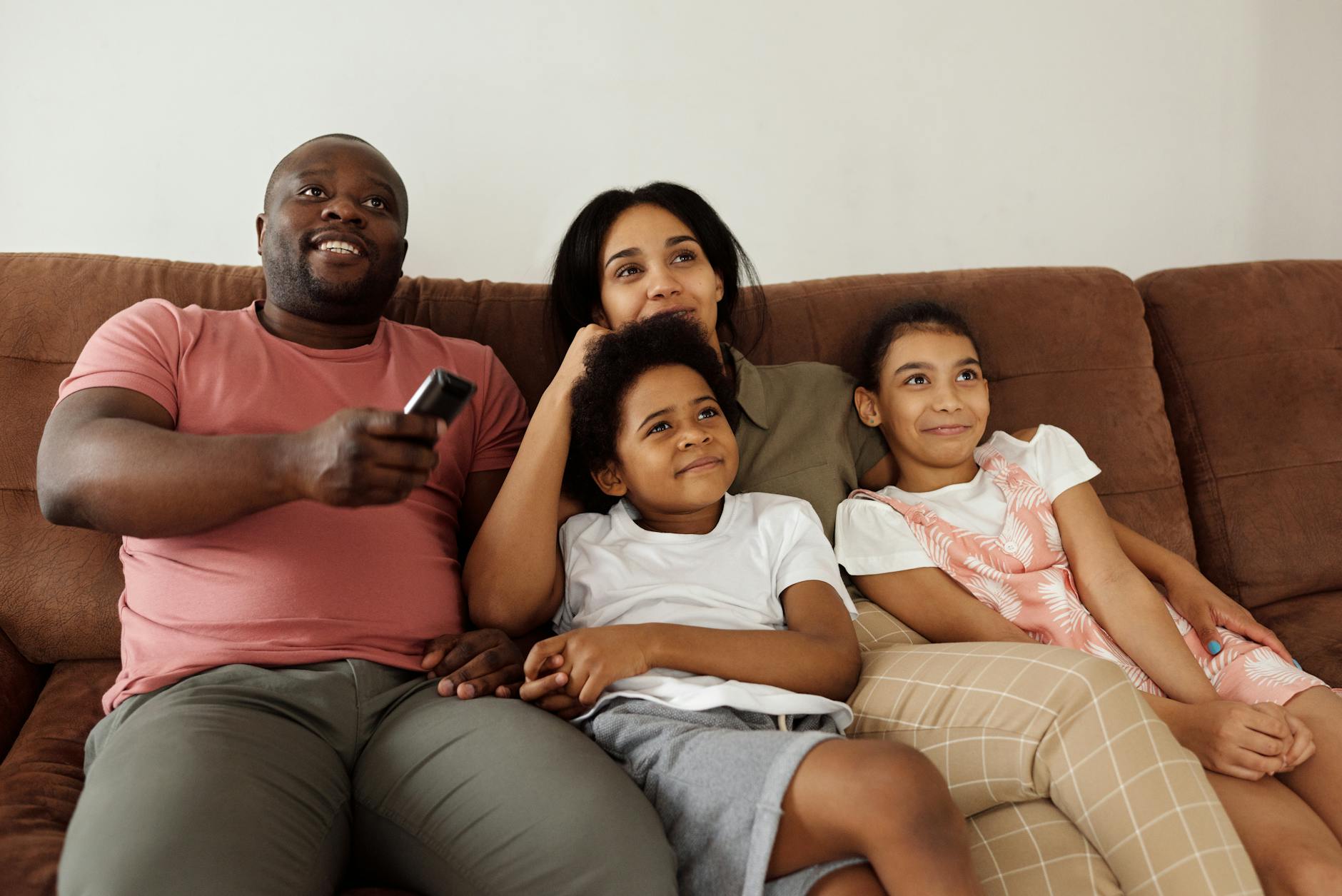 Family on a sofa watching television together, the shared-viewing ritual at the centre of the Bluey minisode debate.