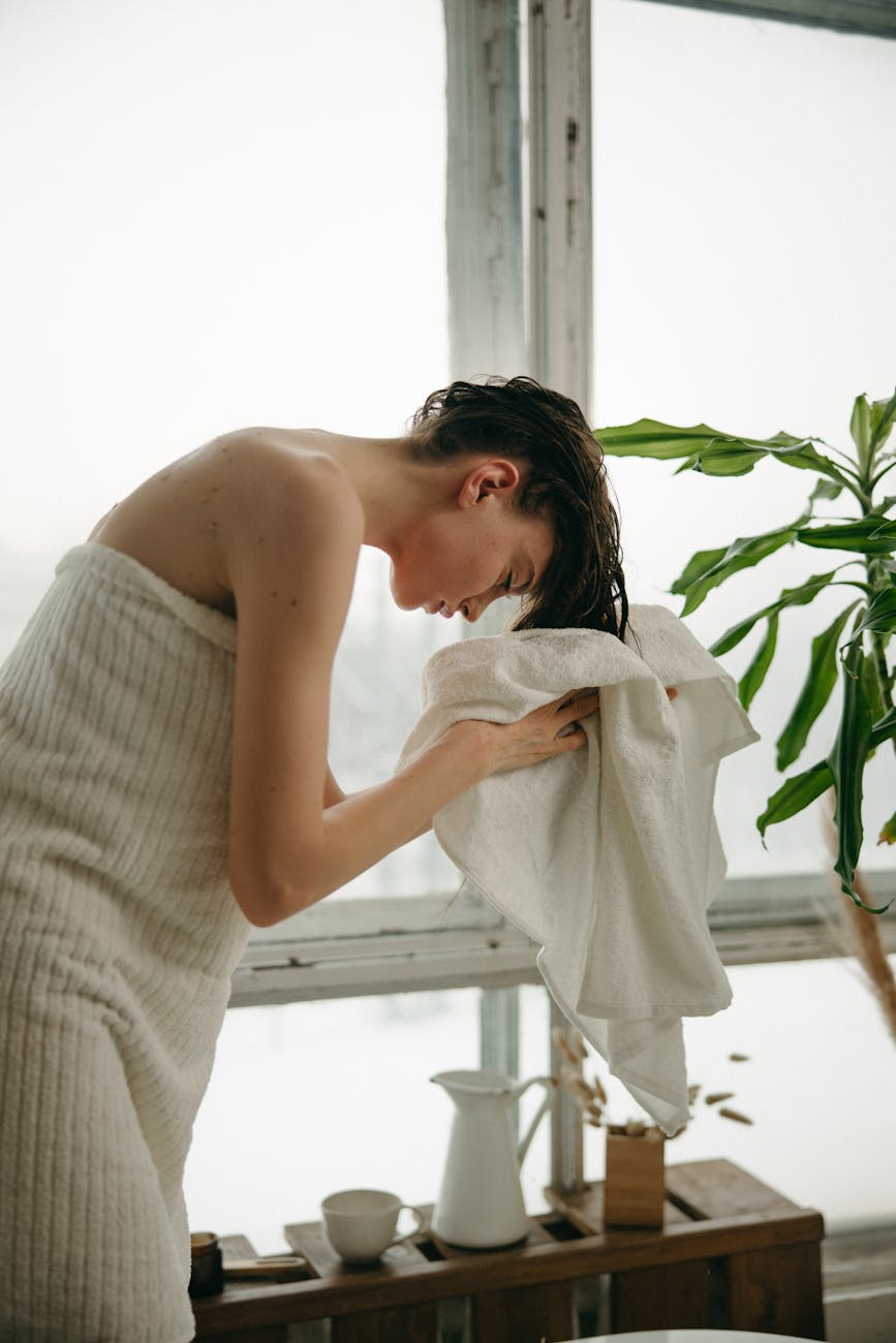 Woman drying her hair by a window during a winter morning routine