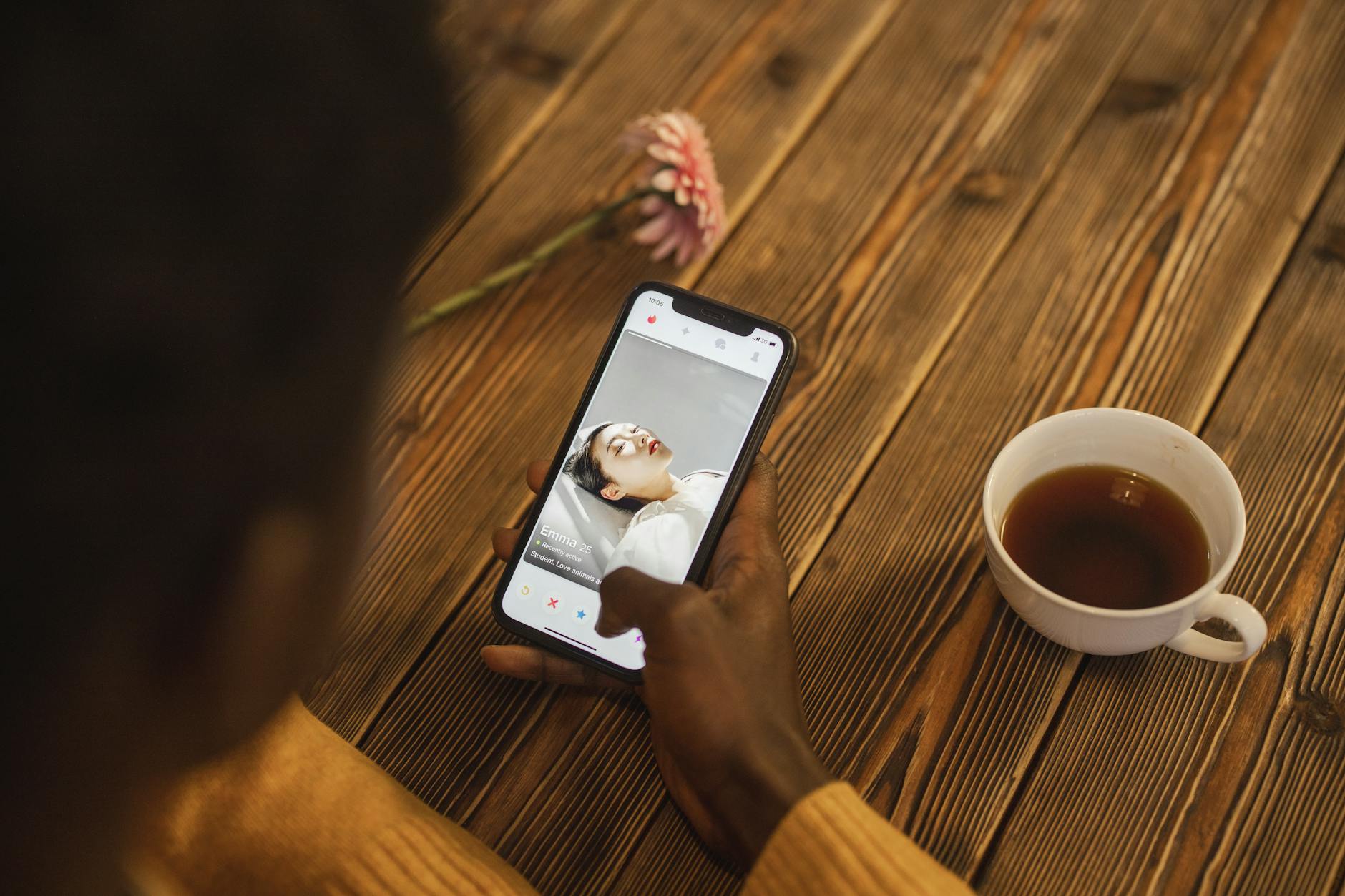 A phone showing a dating app beside a cup of tea, the quiet domestic side of modern courtship.