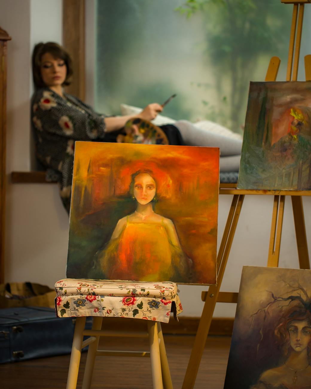 Painter pausing in a studio crowded with half-finished canvases