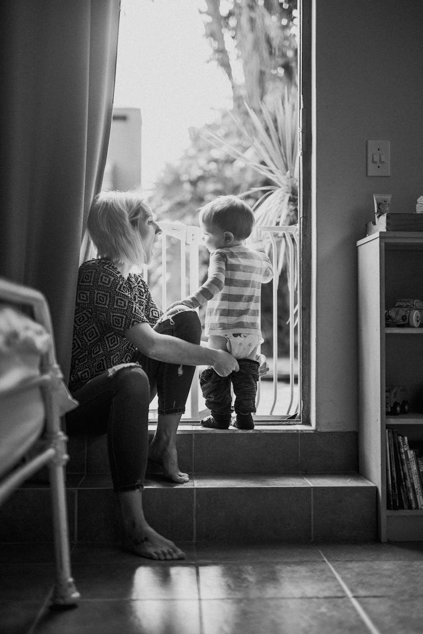 A mother and child share a quiet moment at home, held close in black and white.