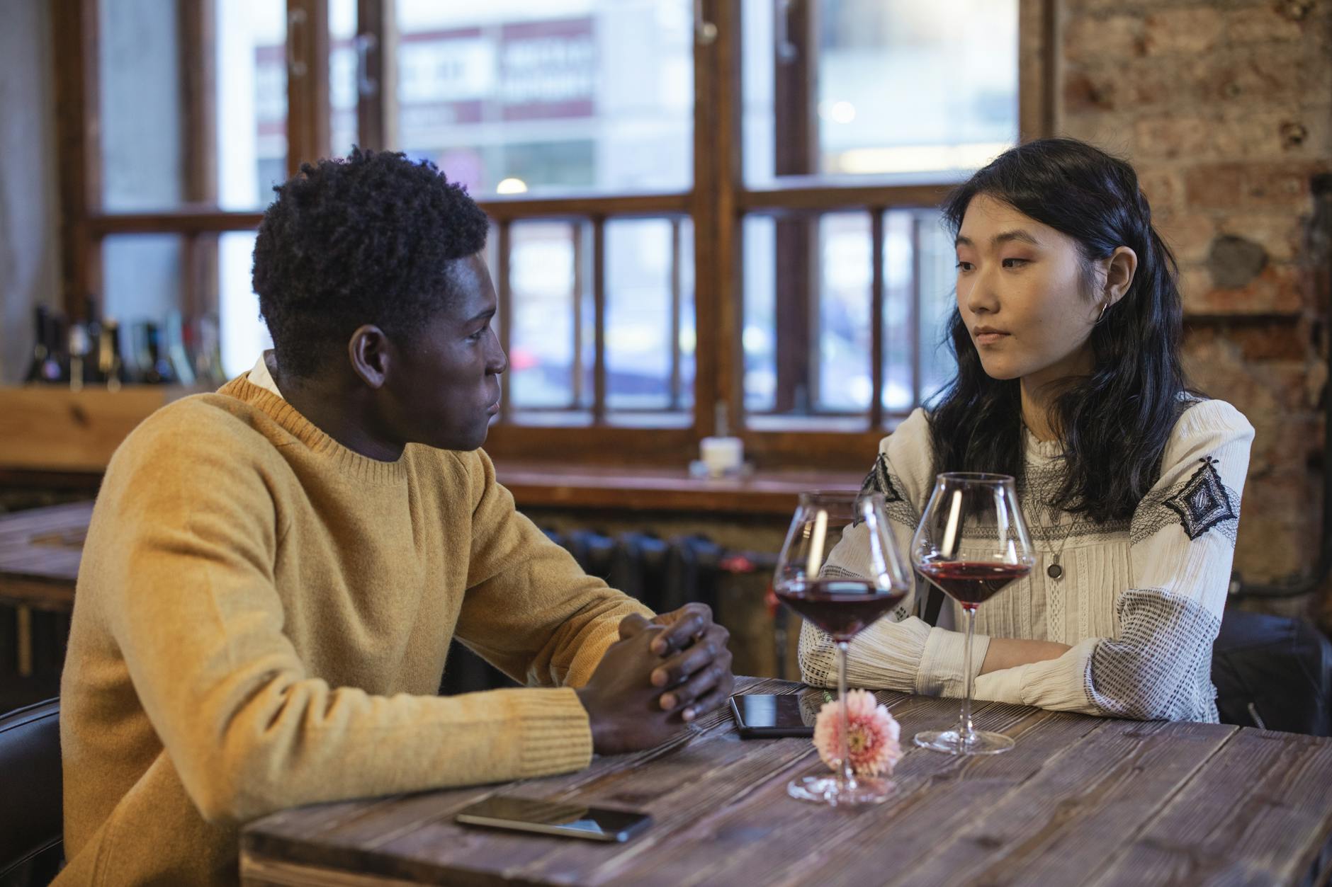 A couple in conversation over wine at a cafe table