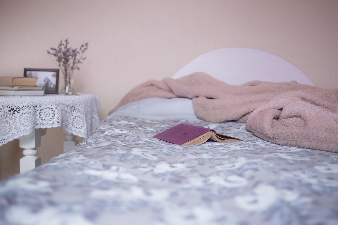 a relaxed bedroom with layered bedding, books and soft linen textures