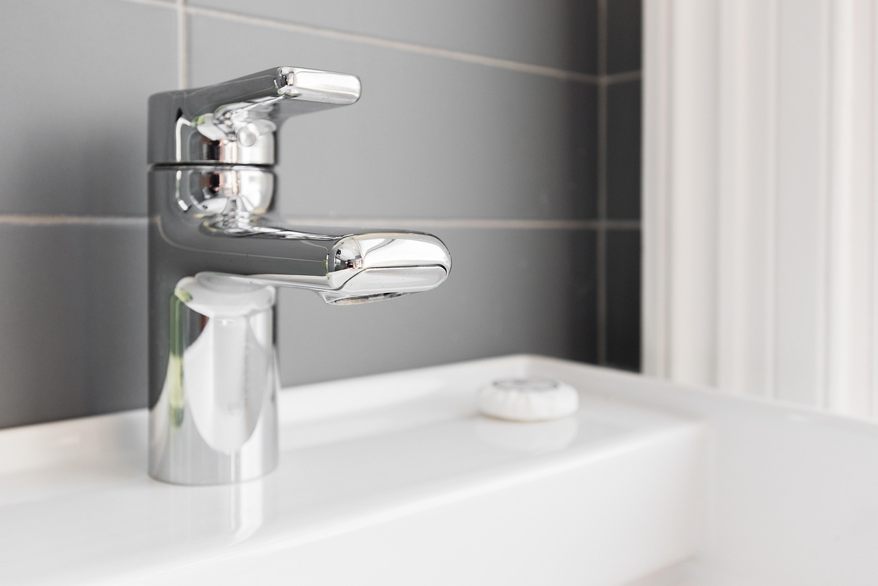 A pared-back bathroom sink and shower setup that shows how a small space can feel clean rather than crowded.
