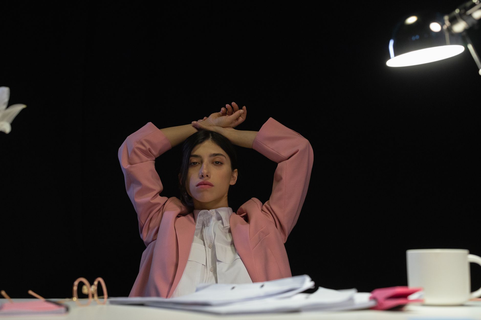 Woman in a pink suit leaning back at an office desk, capturing the small theatre of wearing colour to work.